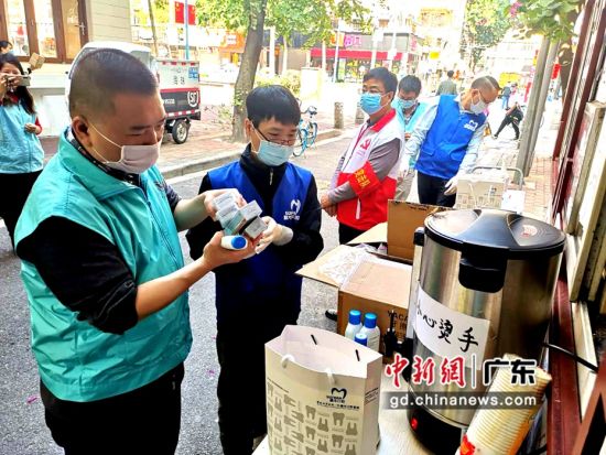 穗華口腔醫院醫務人員與趙廣軍生命熱線志愿者一起給江南中街道青鳳社區值班人員發放防疫物資。(肖金 攝影)